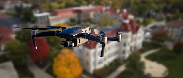 a drone flying in the air with a building in the background.